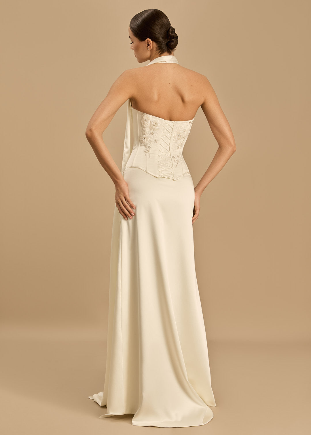 Woman wearing a long, elegant dress with a beige background